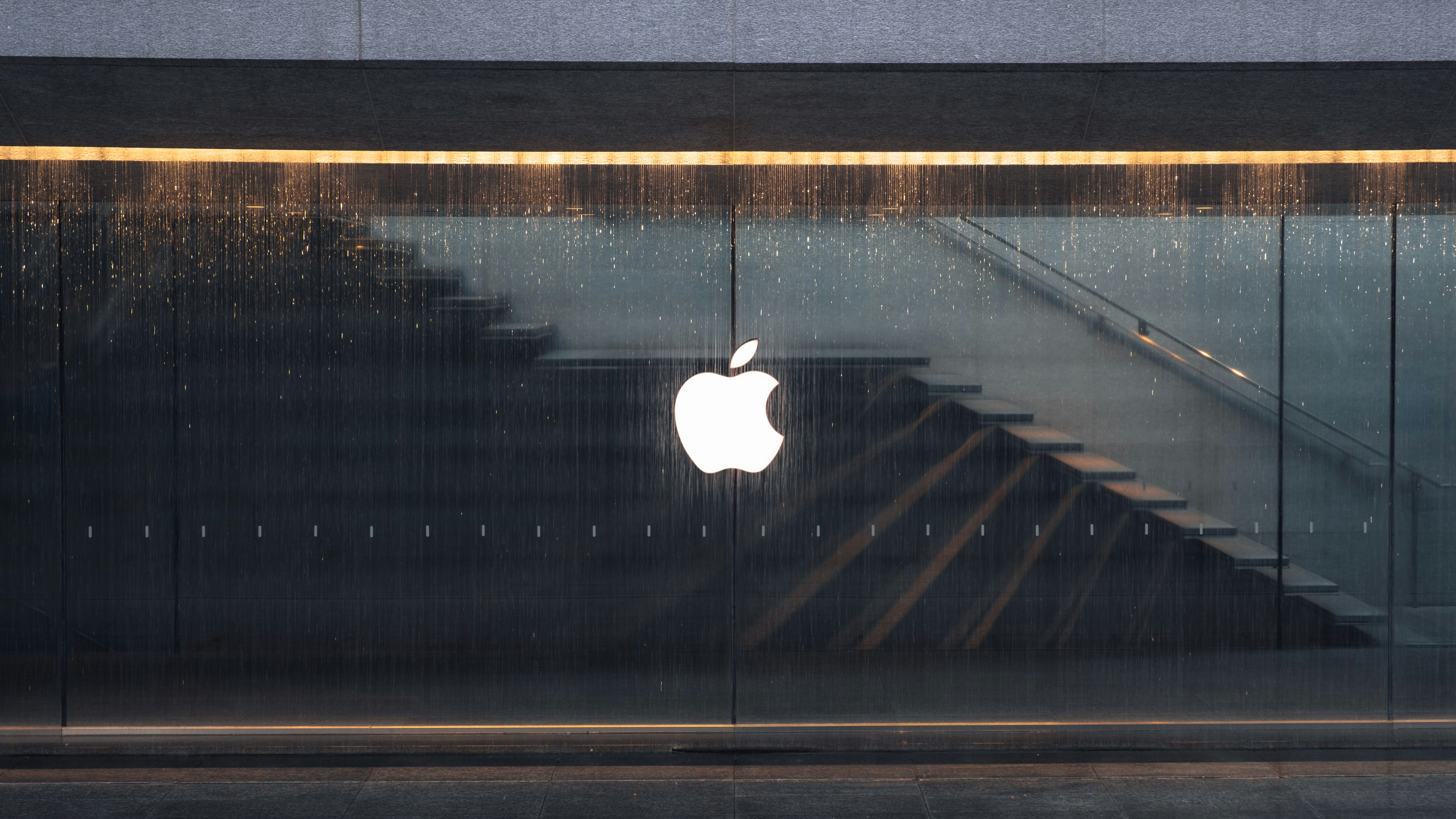 Apple logo on a glass wall near an Apple Store