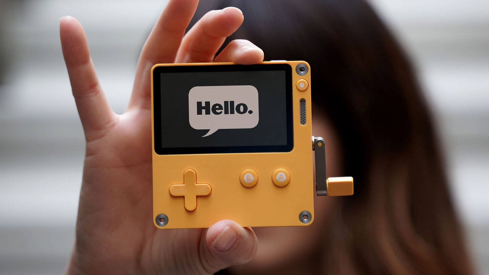 A picture of a Playdate console showing the word Hello on the display